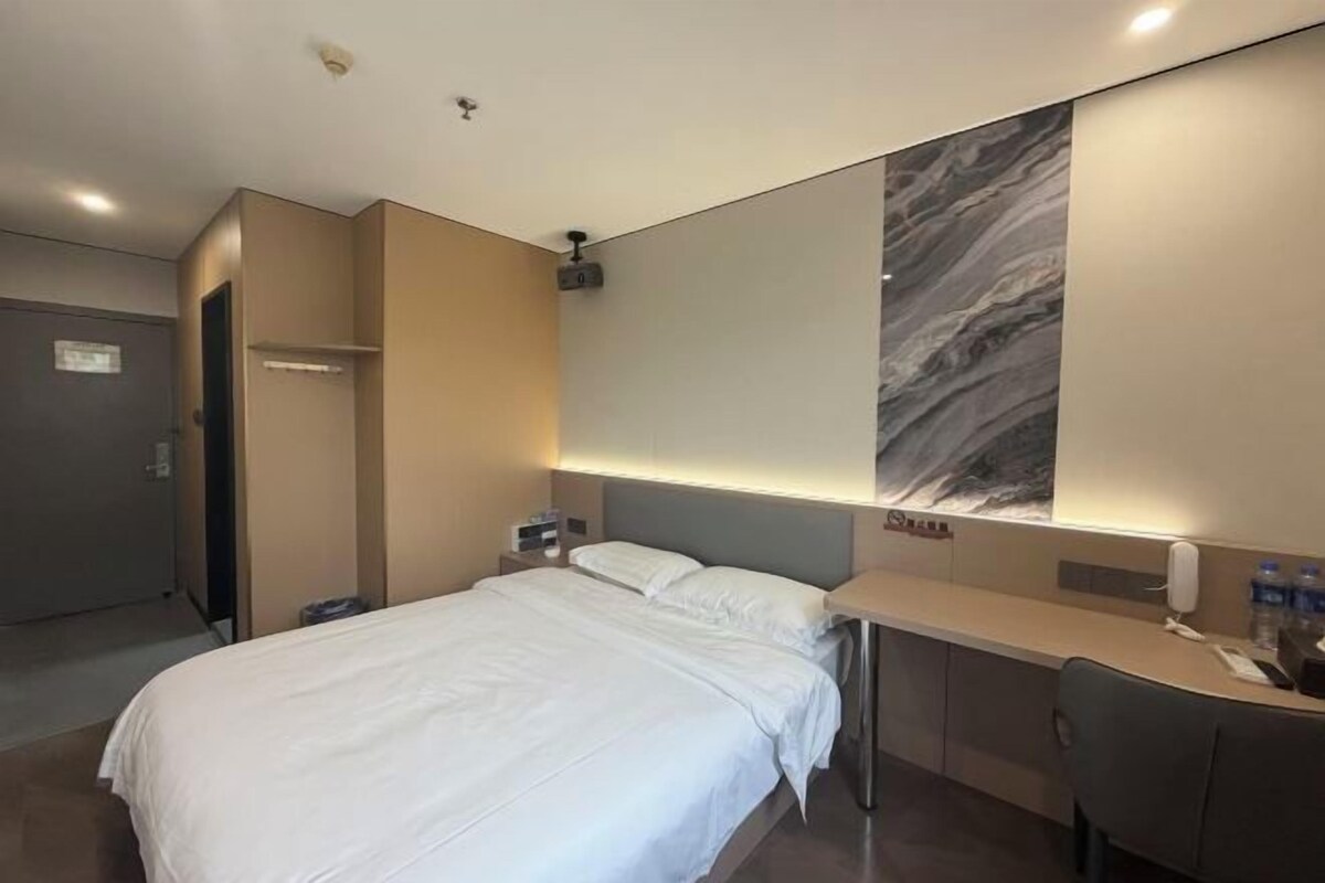 Une chambre d’hôtel comprenant un lit, une table de chevet et une grande œuvre d’art accrochée au mur.