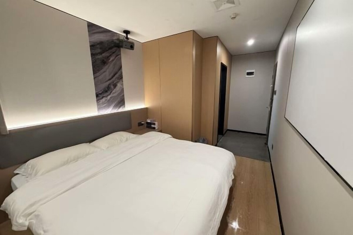 Quarto de hotel com uma cama grande, parede decorada em mármore e design moderno.