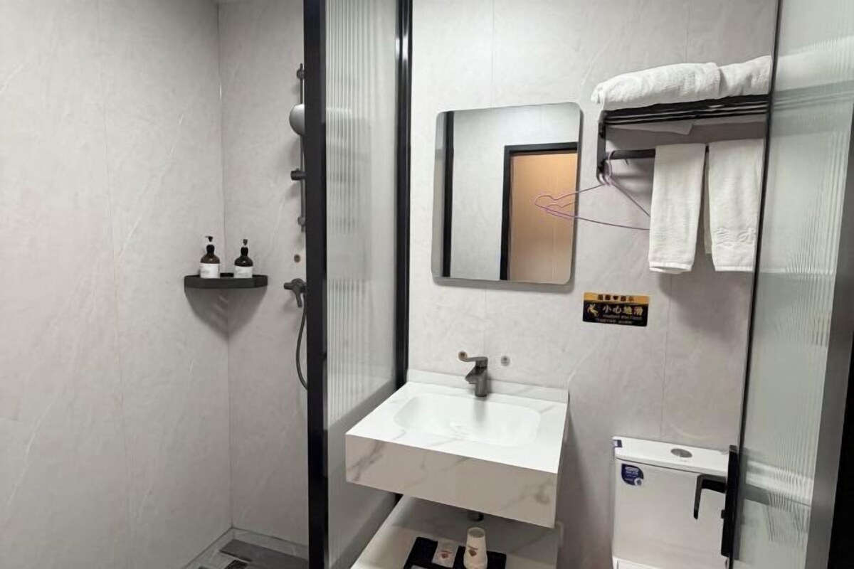 Une petite salle de bain dotée d’une cabine de douche en verre, d’un lavabo blanc et d’un porte-serviettes.