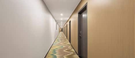 A corridor with a patterned carpet, doors, and recessed lighting.
