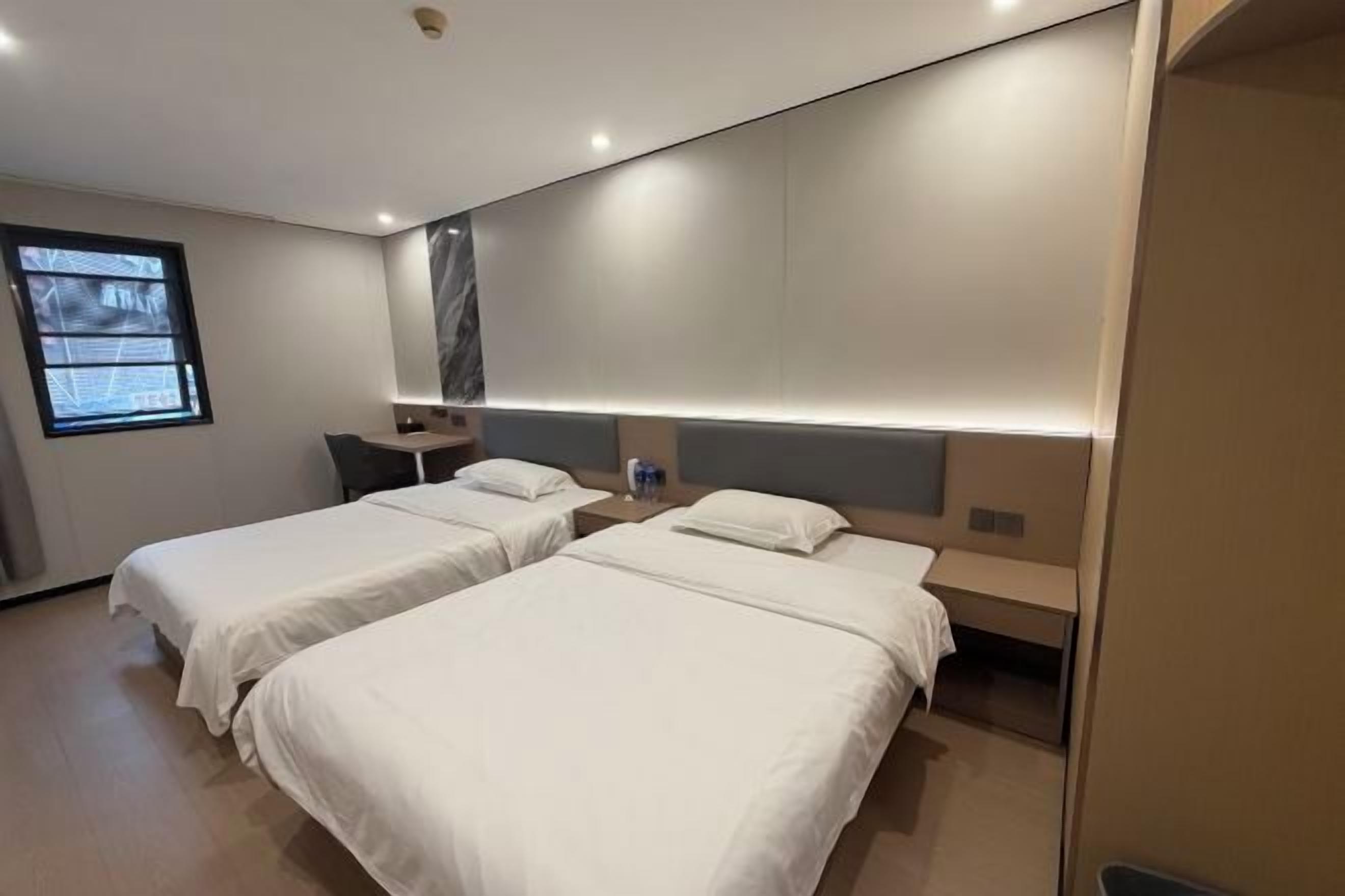 A hotel room with two beds, a desk, and a TV.
