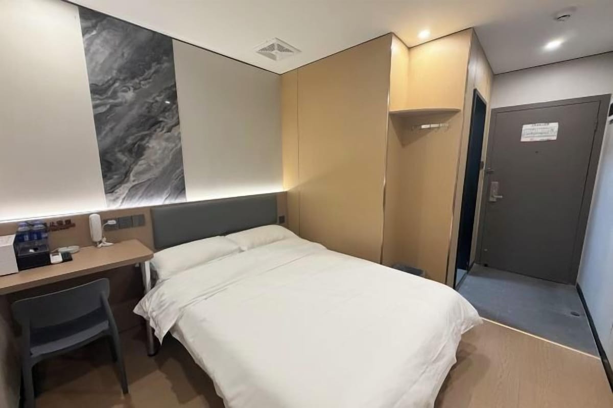 Une chambre d’hôtel avec un lit, un bureau et une armoire.