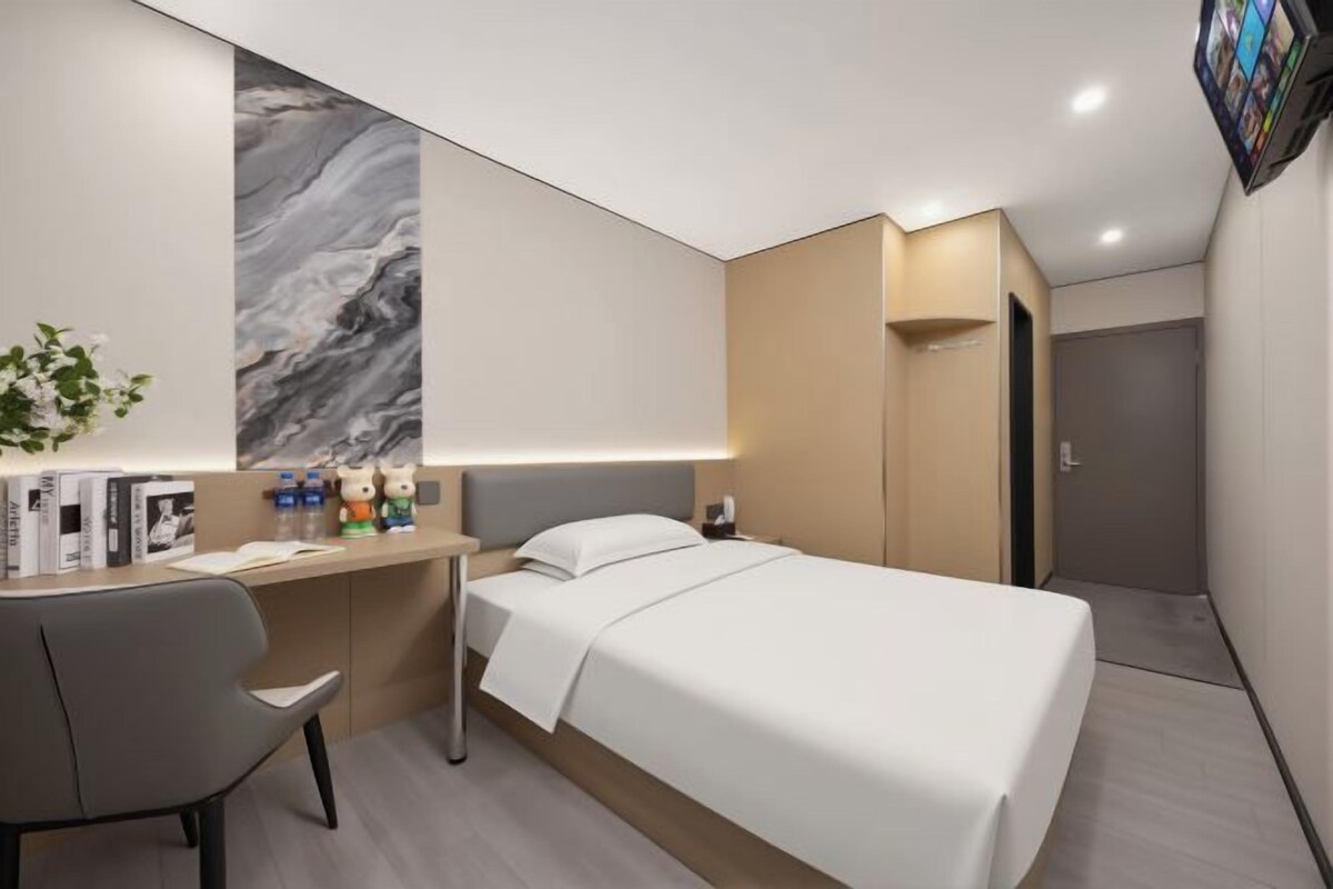 A modern hotel room with a bed, desk, and chair.