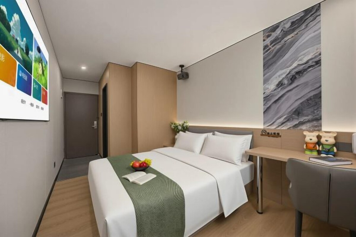 A hotel room with a bed, desk, and a large abstract painting on the wall.