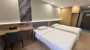 A hotel room with two beds, a desk, and a chair.