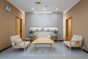 A reception area with a reception desk, two chairs, a sofa, and a wall-mounted artwork. - Qinyue Hotel Changzhou (Changzhou)