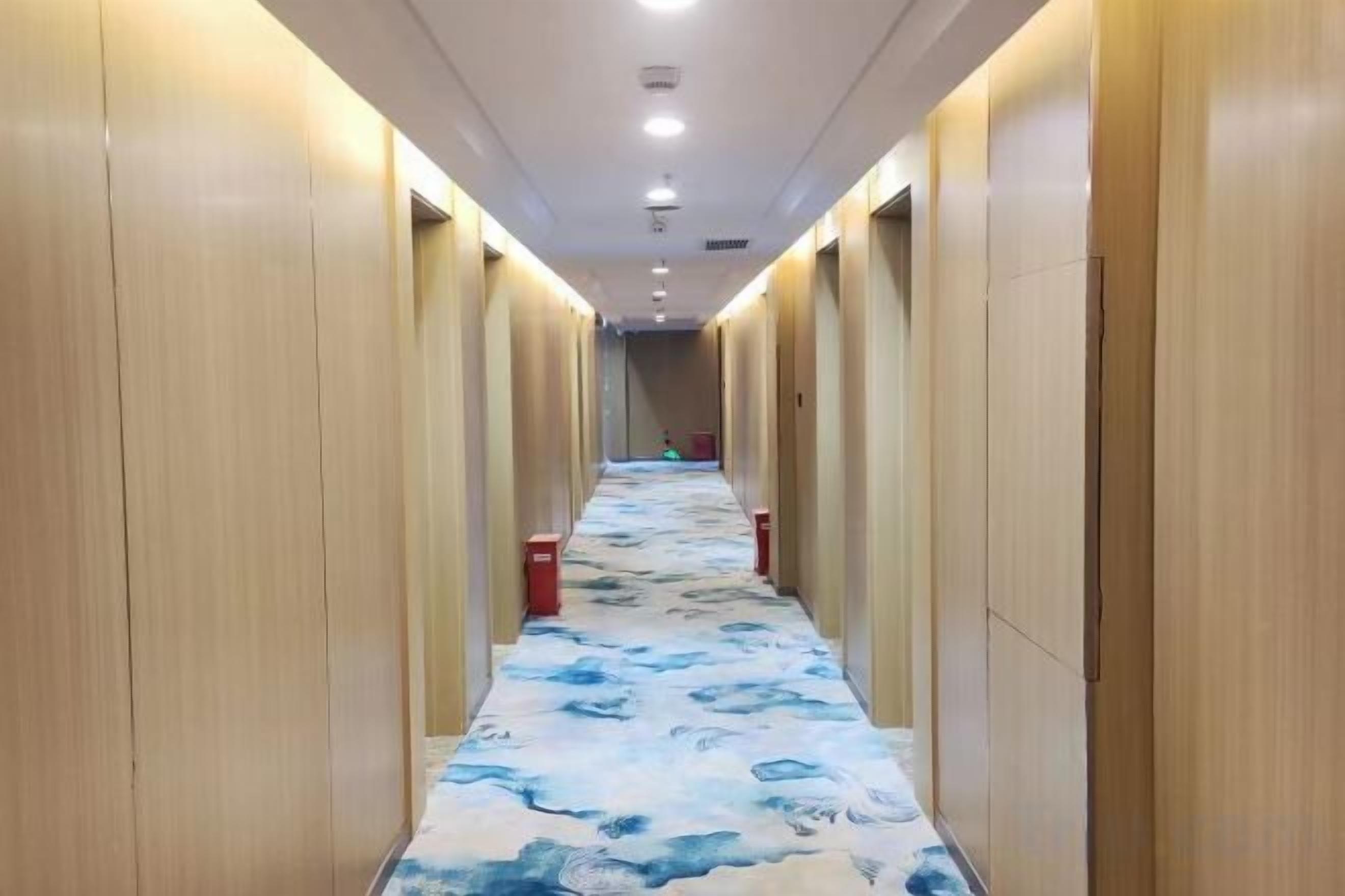 A hotel corridor with wooden walls and a patterned carpet.