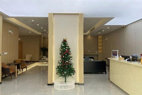 Un moderno vestíbulo de hotel con mostrador de recepción, zona de estar y un árbol decorativo navideño.