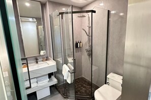 A modern bathroom with a glass-enclosed shower, a white sink, and a toilet.