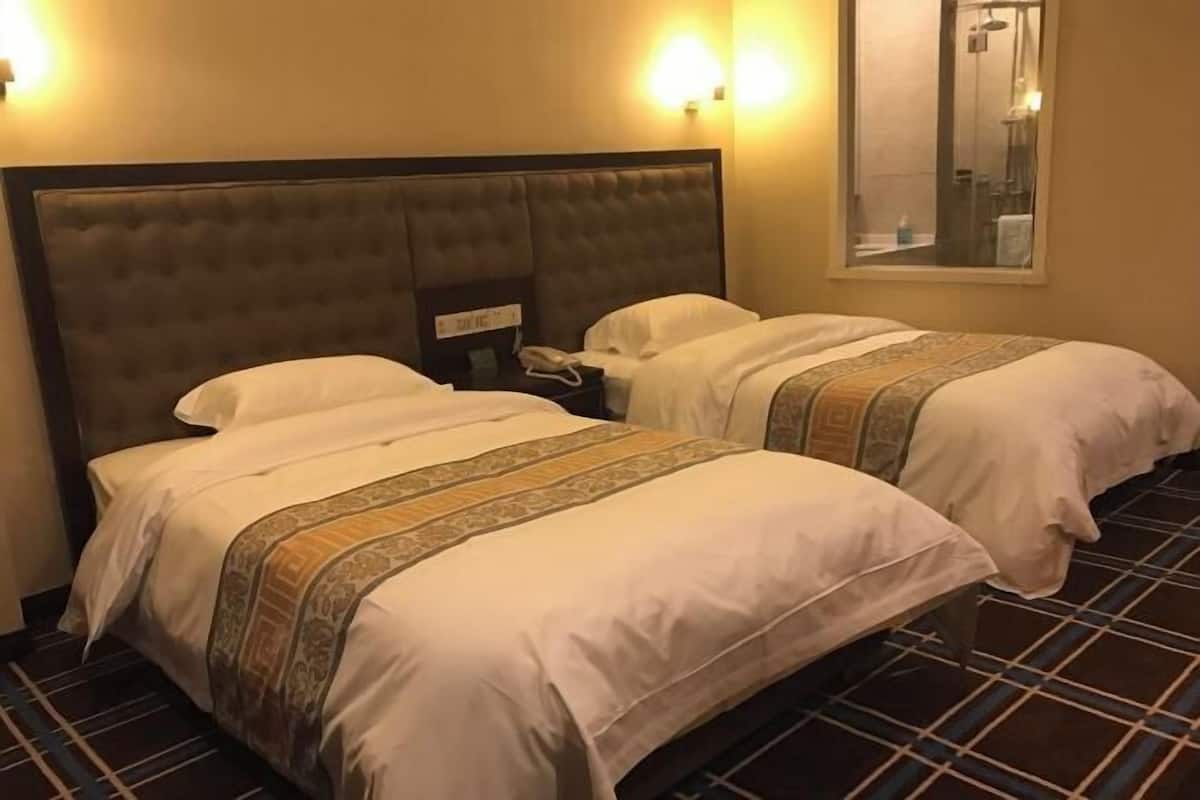 A hotel room with two beds, a headboard, bedside tables, a phone, and a mirror.