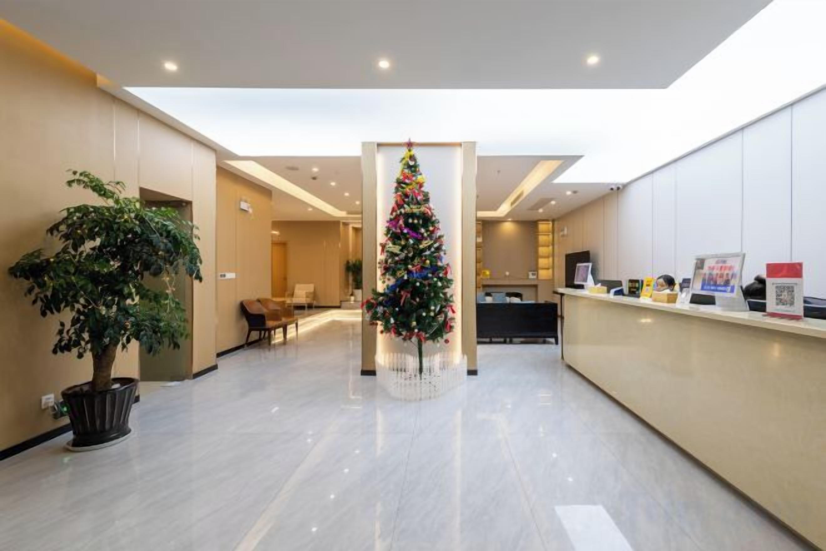 A hotel lobby with a reception desk, a Christmas tree, and a potted plant.