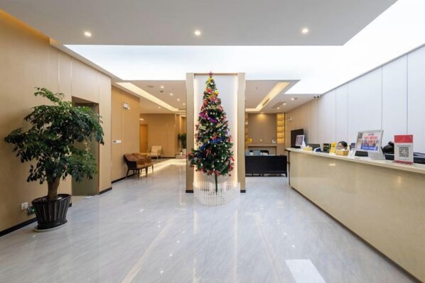 A hotel lobby with a reception desk, a Christmas tree, and a potted plant. - Qinyue Hotel Changzhou (Changzhou)
