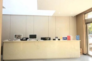 A reception desk with multiple monitors, a telephone, and a few informational cards. - Qinyue Hotel Changzhou (Changzhou)