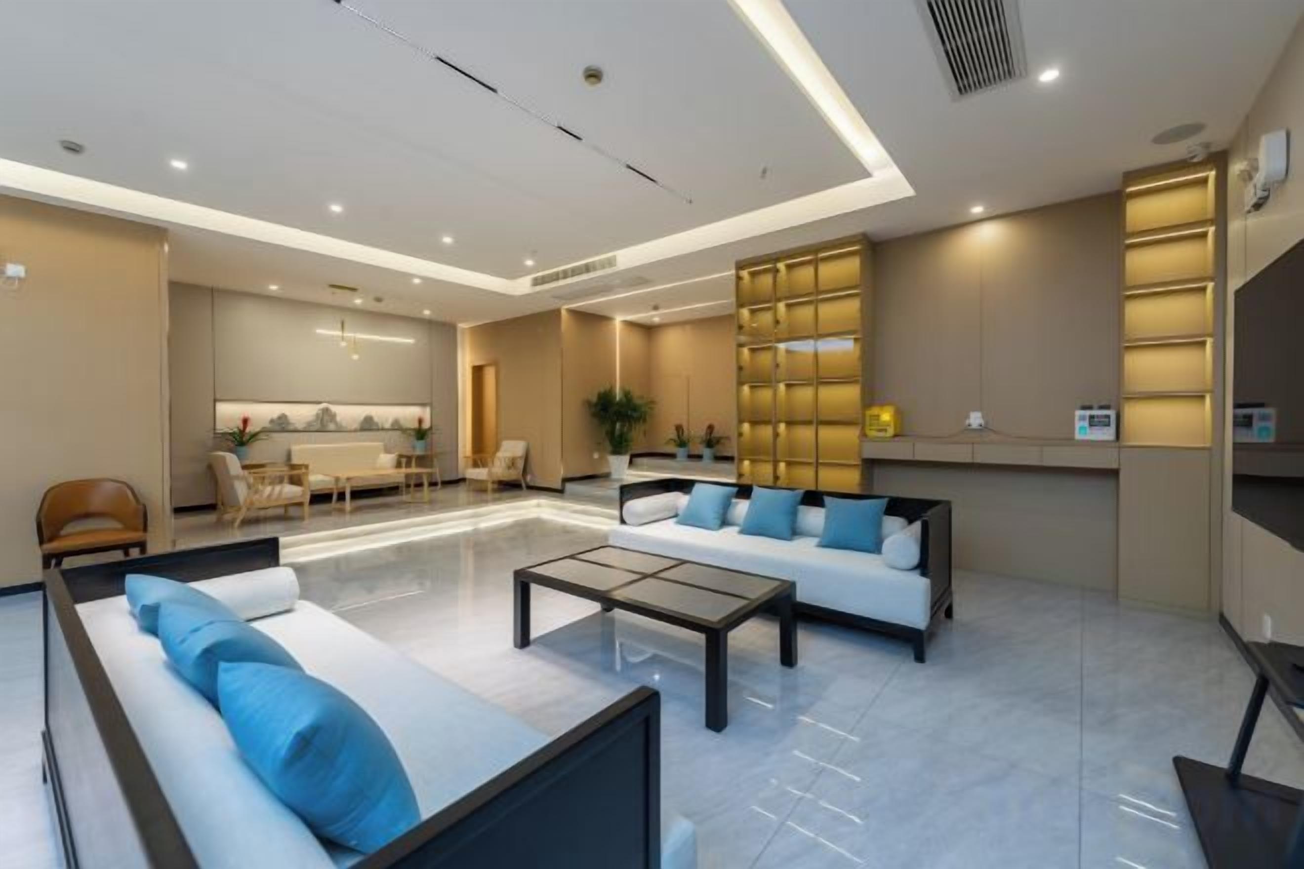 A modern hotel lobby with a reception desk, seating area, and a dining space.
