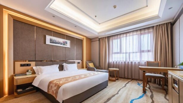 Una habitación de hotel con una cama grande, mesitas de noche, un escritorio y una silla.