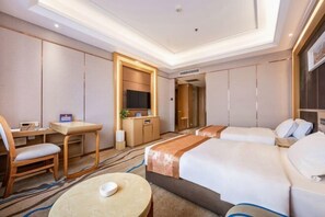 A hotel room with a desk, two beds, a TV, and a mirror. - Wenzhou Hotel (Hotan City)