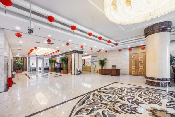 A spacious lobby with a marble floor, a reception desk, and red lanterns.