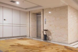 A hotel elevator with marble walls and a patterned carpet.