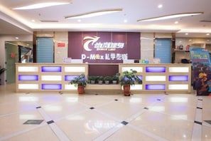 A reception desk with a sign, potted plants, and a tiled floor. - Wenzhou Hotel (Hotan City)