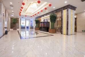 A hotel lobby with a marble floor, a reception desk, and red lanterns on the ceiling.