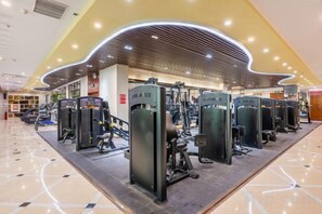 A gym with various exercise machines, a curved ceiling design, and a tiled floor.