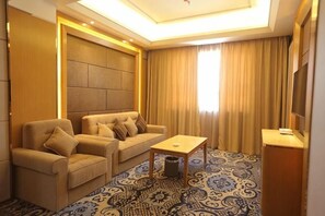 A hotel room with a sofa set, a small table, a TV, and a patterned carpet. - Wenzhou Hotel (Hotan City)