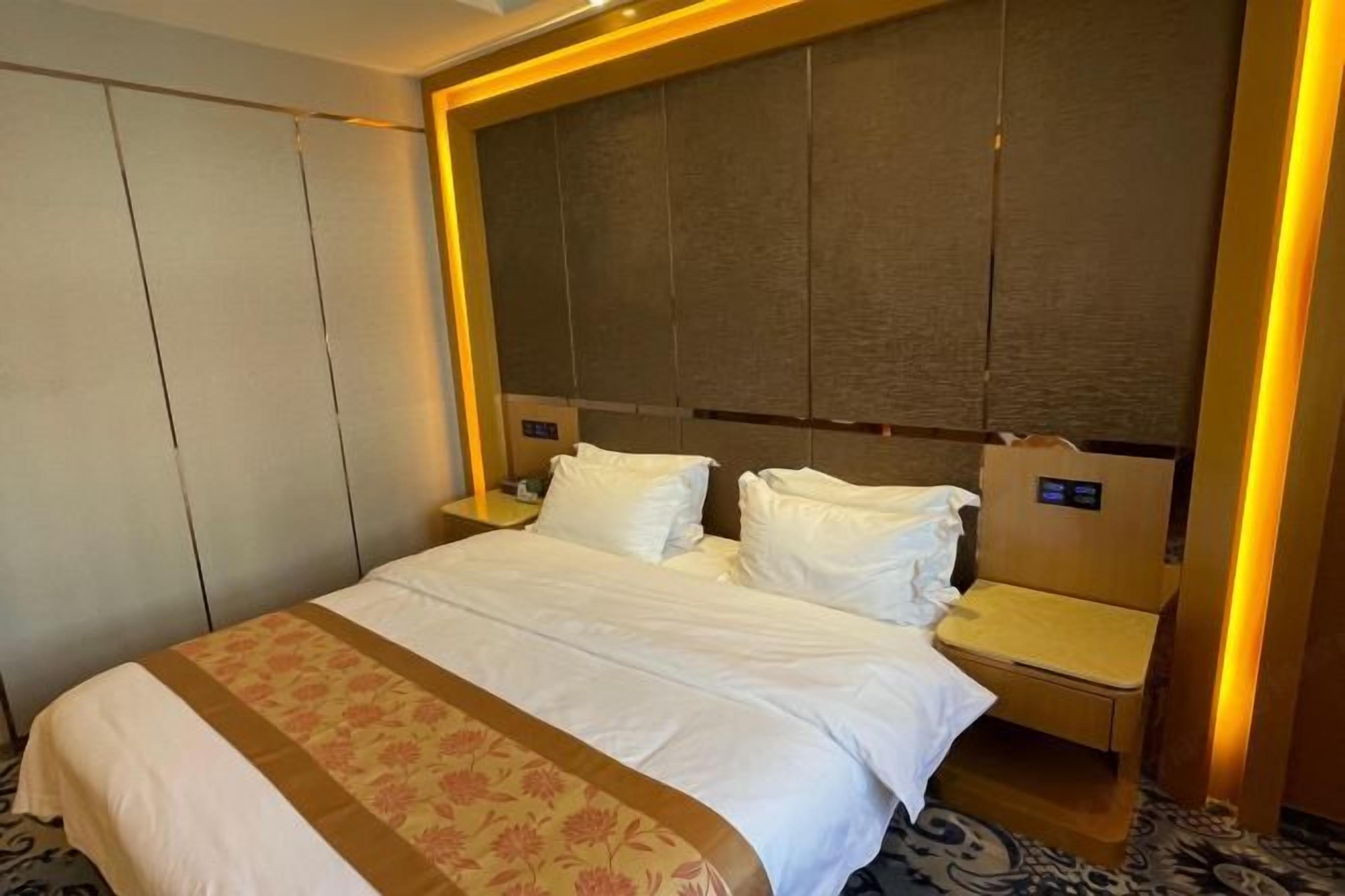 Una habitación de hotel con una cama grande, una mesita de noche y un cabecero.