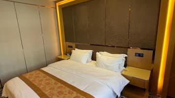 Una habitación de hotel con una cama grande, una mesita de noche y un cabecero.