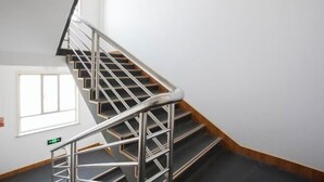 Una escalera con barandillas metálicas y peldaños de madera que conduce a un piso superior.