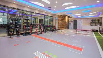 A gym with exercise equipment, a basketball court, and a reception area with a stone wall.