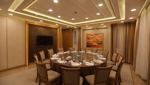 A conference room with a round table, chairs, a flat-screen TV, and a desert-themed painting. - Wenzhou Hotel (Hotan City)