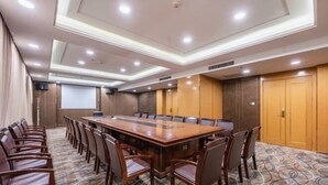 A conference room with a large wooden table, rows of chairs, and a projector screen. - Wenzhou Hotel (Hotan City)