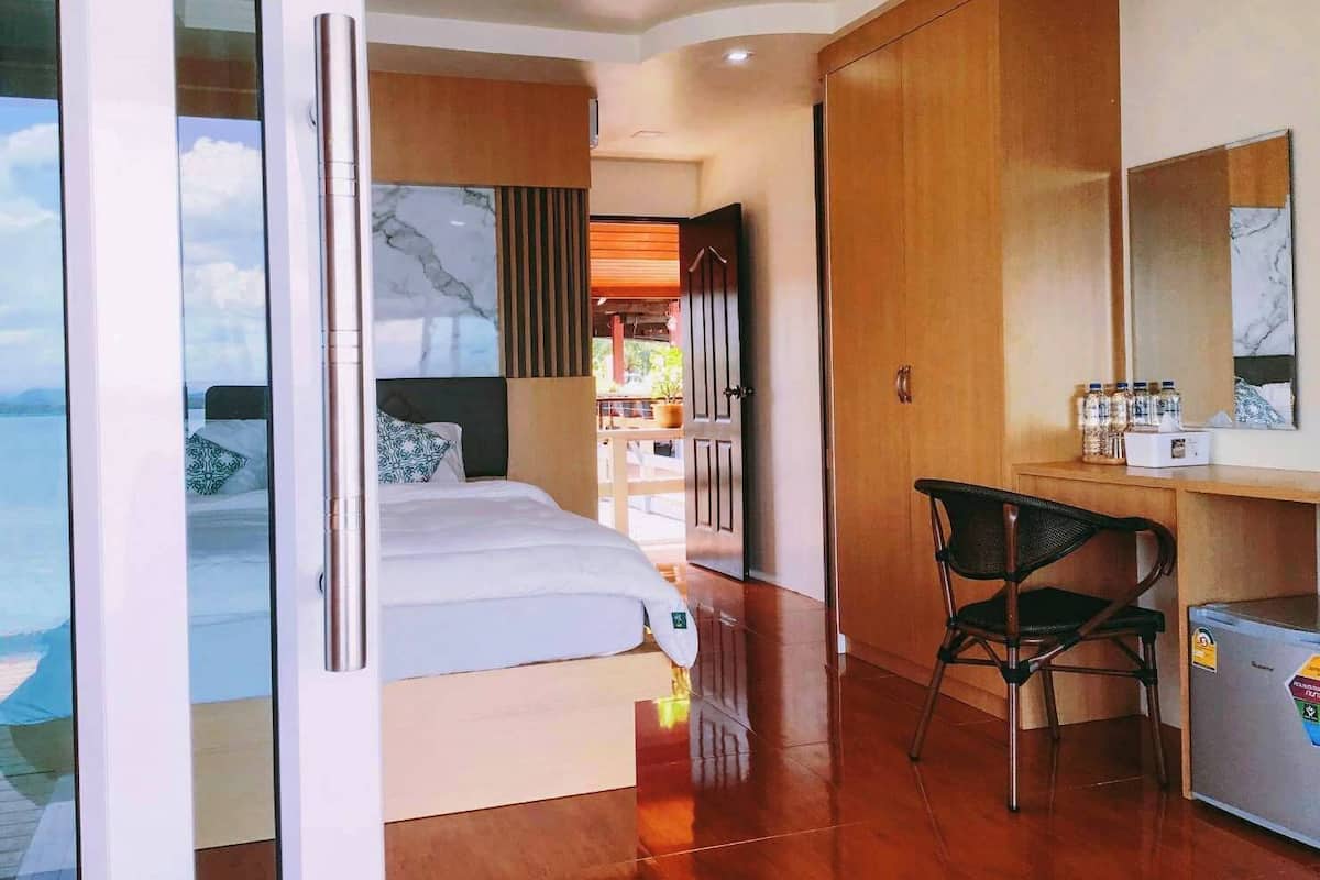 A modern hotel room with a bed, a desk, a chair, and a minibar.
