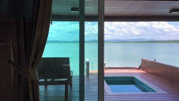 Une pièce avec vue sur une vaste étendue d’eau, une terrasse en bois et une petite piscine.