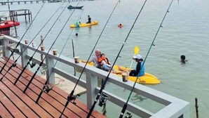 Une jetée en bois avec des cannes à pêche et un kayak jaune.