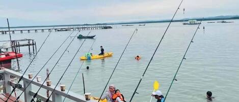 A wooden pier with fishing rods and a yellow kayak.