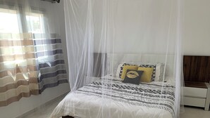Un lit bien fait, doté d’un baldaquin, d’une table de chevet et d’une petite table de nuit.