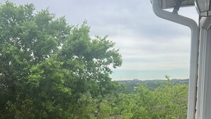 A wooden deck with a railing, overlooking a lush green landscape. - Beautiful 4 bedroom 3.5 bath Home 5 minutes from Down Town Austin. (Austin)