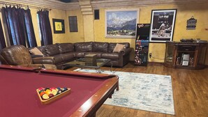 A living room with a pool table, a leather sofa, a coffee table, and a carpet. - Beautiful 4 bedroom 3.5 bath Home 5 minutes from Down Town Austin. (Austin)