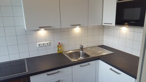 Une cuisine moderne avec des meubles blancs, un évier en acier inoxydable et un four Bosch.