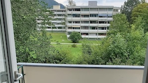 Un balcón con dos sillas y vistas a un edificio de varios pisos al fondo.