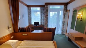 Una habitación de hotel con una cama grande, un escritorio con computadora, una silla y una mesita.