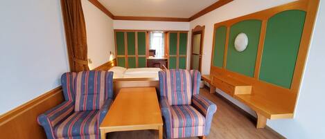A room with a wooden table, striped armchairs, a bench, and a green panel wall.