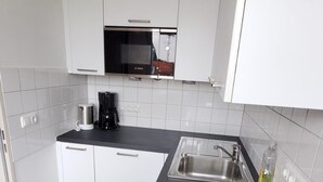 A modern kitchen with white cabinets, a black countertop, a Siemens induction cooktop, a coffee maker, and a sink. - Apartment 304, apartment, 38 sqm, 1-2 persons, balcony (Bad Reichenhall)