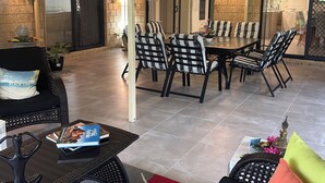 Un vaste espace patio aménagé avec une table et des chaises, un canapé et un ventilateur.