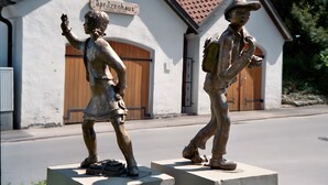 Zwei Bronzestatuen von Kindern vor einem Gebäude mit dem Schild 'Spritzenschloss'.