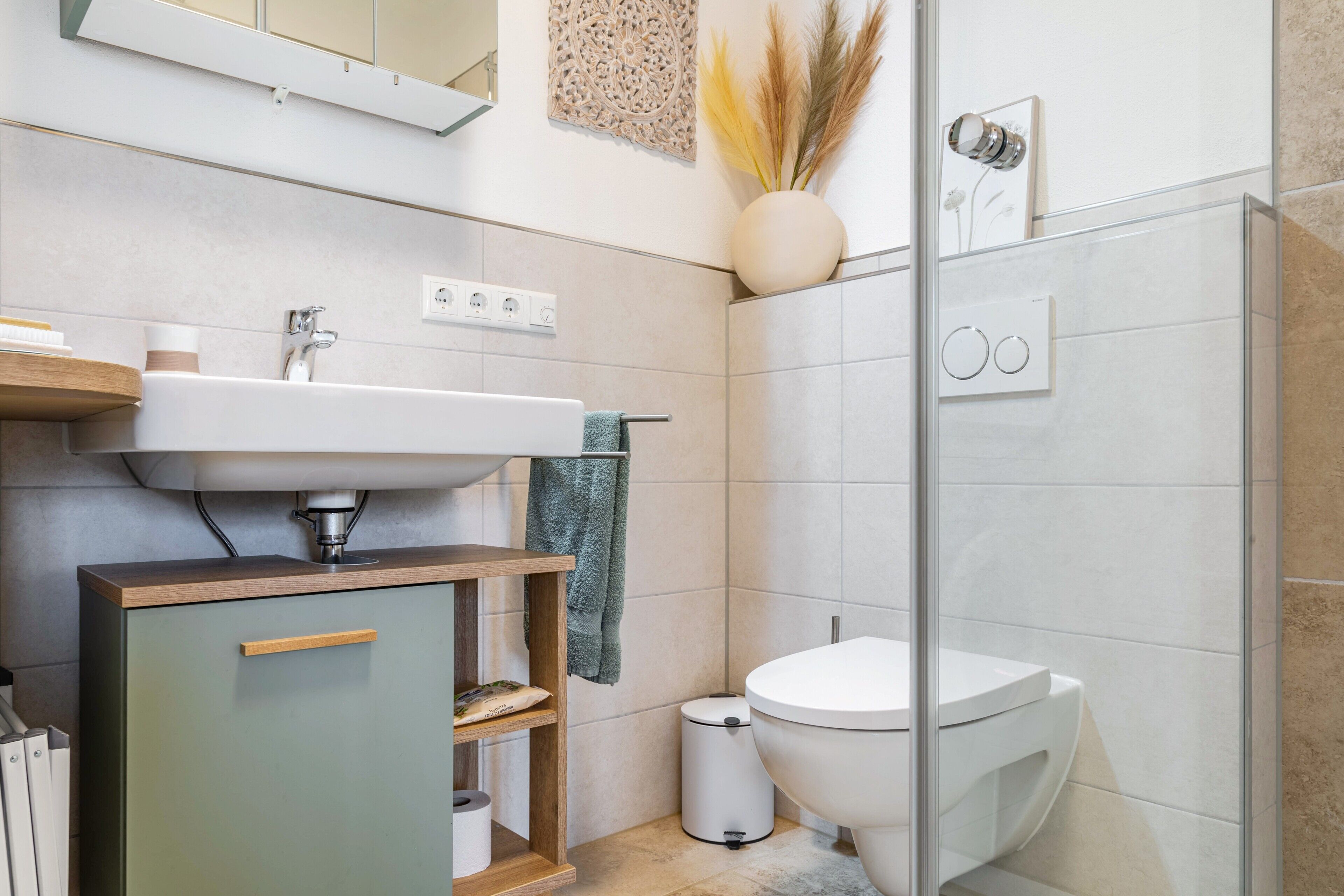 Een moderne badkamer met een wastafel, toilet en douche.