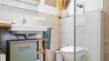 Een moderne badkamer met een wastafel, toilet en douche.