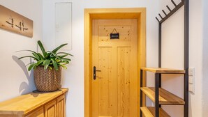 Une porte en bois avec une petite pancarte, une plante en pot et une étagère en bois.