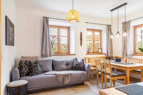 Un salon moderne comprenant un canapé, une table à manger, des chaises et un luminaire suspendu.